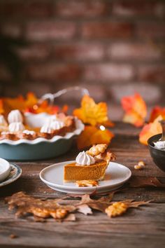 pumpkin pie with whipped cream on top sitting on a table next to other plates and bowls