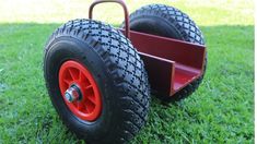 an orange wheelbarrow is sitting in the grass on top of it's wheels