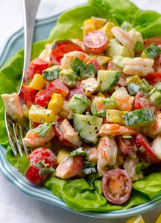 a salad with shrimp, cucumber and tomatoes on it is shown in close up