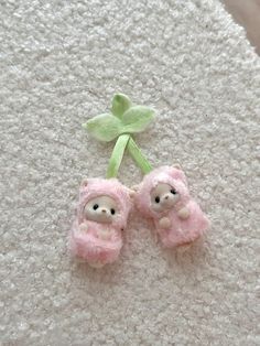 two small pink teddy bears laying on top of a white carpet