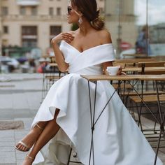 a woman sitting at a table in a white dress