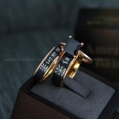 two gold rings with black onyxite stones are sitting on top of a box