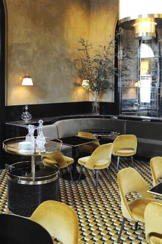 an elegant restaurant with yellow chairs and round tables in the center, surrounded by black and white checkered flooring