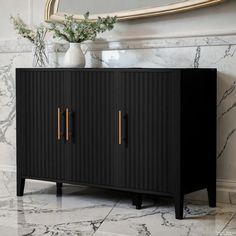 a black cabinet with gold handles in front of a mirror and marble wallpapered floor