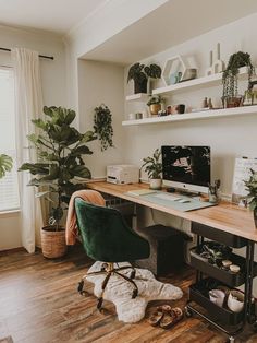 a desk with a computer on top of it next to a plant and other items