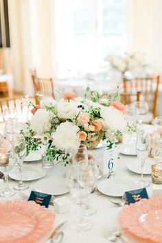 the table is set with plates, silverware and flower centerpieces for an elegant wedding reception