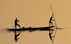 two people on a boat in the middle of water with poles sticking out of it