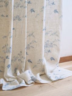 a curtain with blue flowers on it in front of a wooden floor