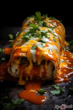 a burrito covered in cheese and cilantro on a black surface with sauce