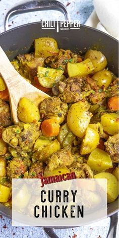 a pan filled with curry and potatoes on top of a blue countertop next to a wooden spoon