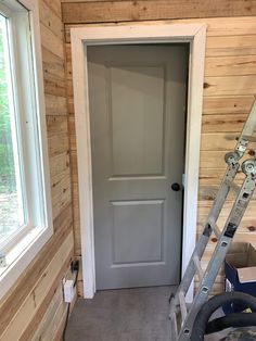 a door being installed in a room with wood paneling and ladders on the floor