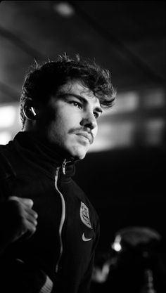 a black and white photo of a man in a track suit looking off to the side