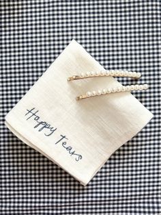 two napkins with happy tears written on them sitting on top of a blue and white checkered table cloth