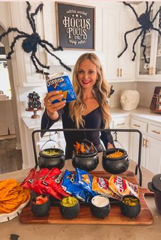 a woman standing in front of a table filled with halloween food and snacks on it