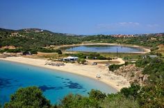 an aerial view of a sandy beach with clear blue water and lots of green trees