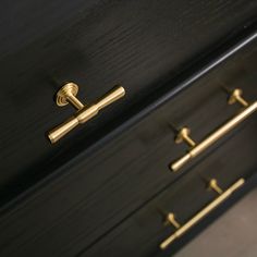 a black dresser with brass handles and knobs on the drawer pulls is seen in this image