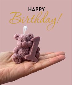 a pink teddy bear sitting on top of a birthday candle in someone's hand