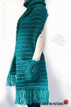 a crocheted scarf with fringes hanging on a white wall next to a mannequin's head