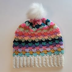 a multicolored crocheted hat with a white pom - pom