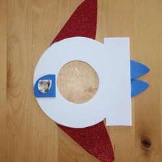 a paper rocket ship on top of a wooden floor with a hole in the middle