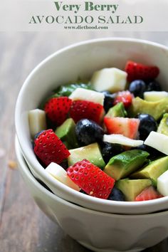 a white bowl filled with fruit salad on top of a wooden table