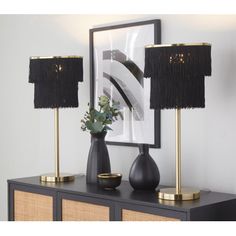 two black and gold lamps sitting on top of a dresser