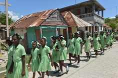 a group of girls in green dresses walking down the street