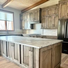 a large kitchen with wooden cabinets and marble counter tops, along with an island in the middle