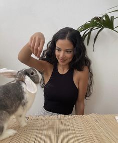 a woman standing next to a rabbit on top of a table