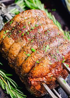 a piece of meat is being cooked on a grill with tongs and garnishes