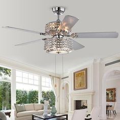 a living room with white furniture and a ceiling fan in the middle of the room