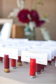 red candles are lined up on a table with place cards in front of the candles