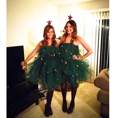 two women dressed in green dresses standing next to each other with christmas decorations on them