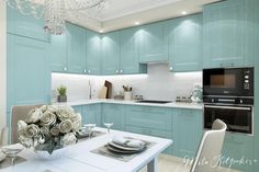 a white table and chairs in a room with blue cabinets, chandelier and an oven