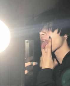 a person sticking their tongue out in front of a mirror with light shining on them