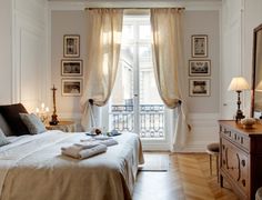 a bed room with a neatly made bed next to a window and a wooden dresser