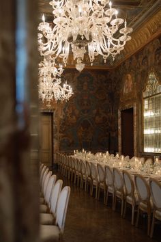 an elegant dining room with chandelier and white tablecloths set for a formal dinner