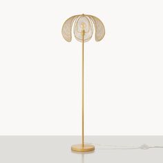 a floor lamp with a gold metal base and an intricately designed flower design on the top