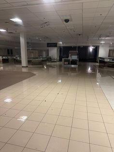 an empty room with white tile floors and lights on the ceiling is seen in this image