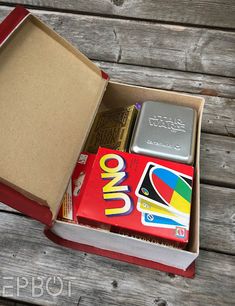 an open red box with various items in it on a wooden table next to a book