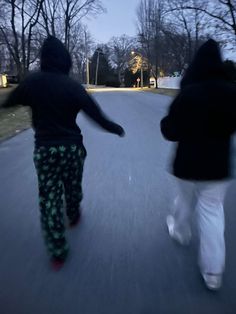 two people are running down the street at night