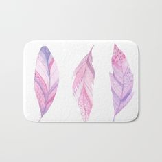 three pink and purple feathers on white bath mat