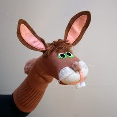 a stuffed animal that looks like a donkey with green eyes and nose is being held up by someone's hand