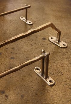 two metal brackets sitting on top of a floor