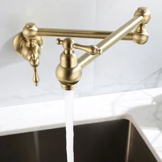 a faucet that has water running from it in a kitchen sink with marble counter tops