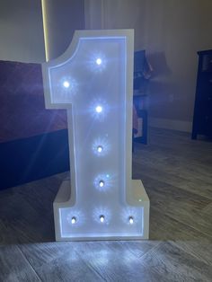 a lighted number one sitting on top of a wooden floor in front of a wall