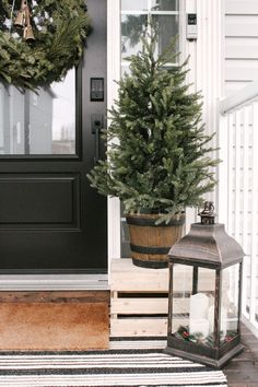 a christmas tree sitting on top of a porch next to a lantern