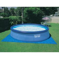 an inflatable swimming pool is shown on the grass with a blue mat around it