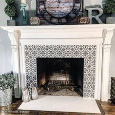 a fireplace with a clock above it and some plants on the mantels next to it