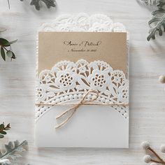 a wedding card with lace on it and a ribbon tied around the front, sitting on top of a wooden table